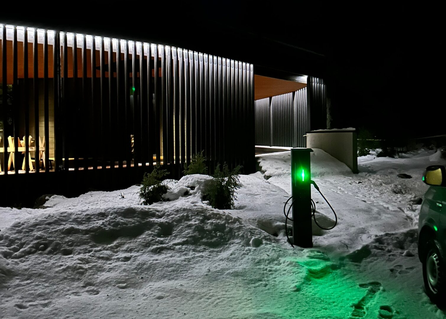 Sähkövirta Boströmin asentama sähköauton latausasema. Pimeä ilta ja talvinen maisema.